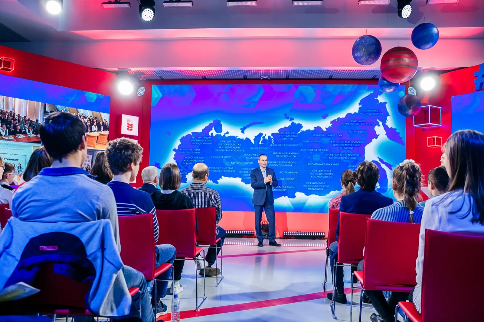 Broadcast studio: on the left, a video link screen showing a site in another city